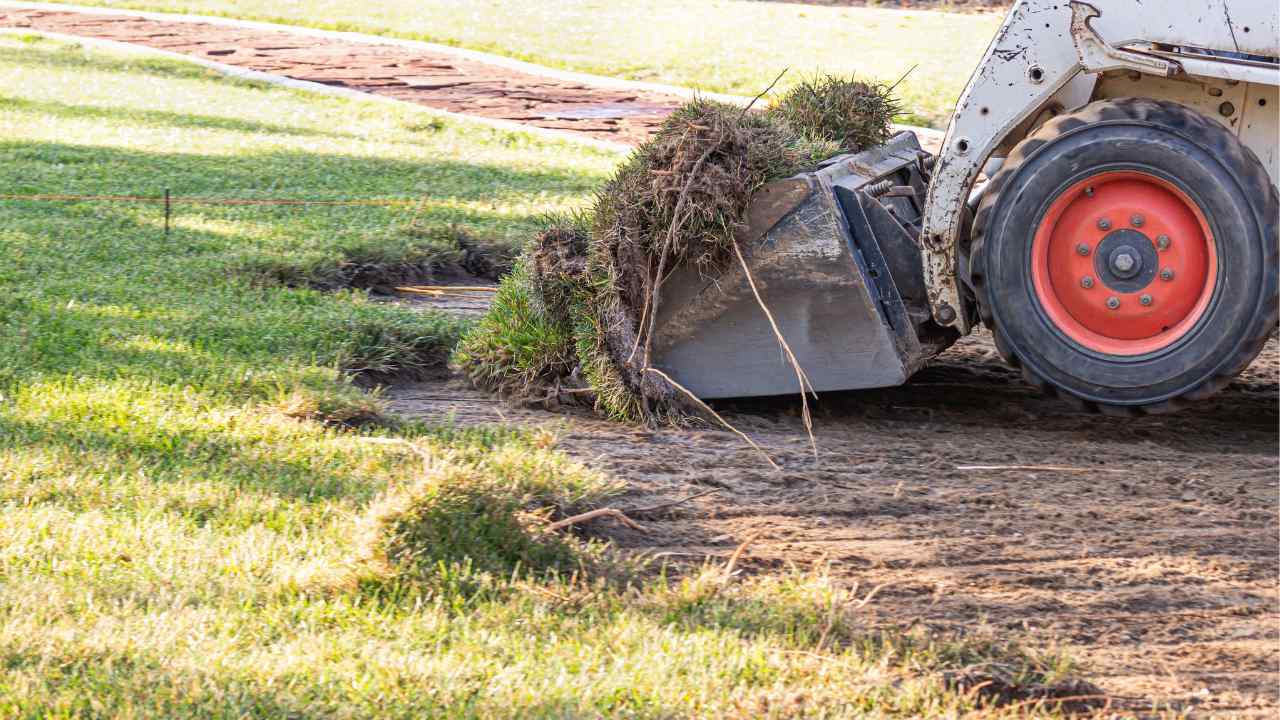 an excavator digging up dirt in a yard